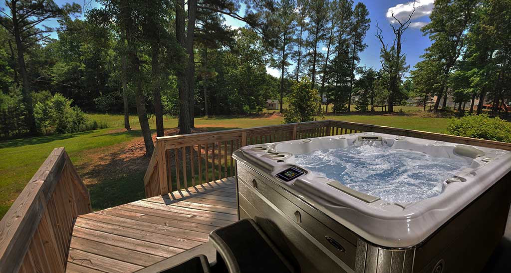 Spa H679 posé sur une grande terrasse en bois avec une vue sur la foret.