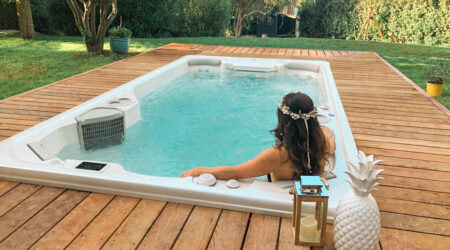 Une femme se détend dans un spa de nage installé en extérieur.