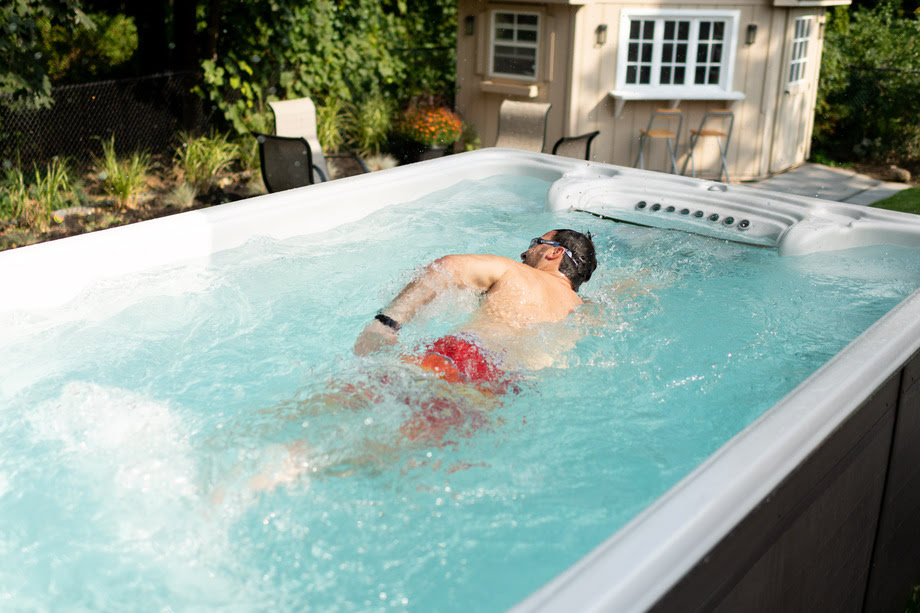 Un homme nage dans une mini piscine (spa de nage)