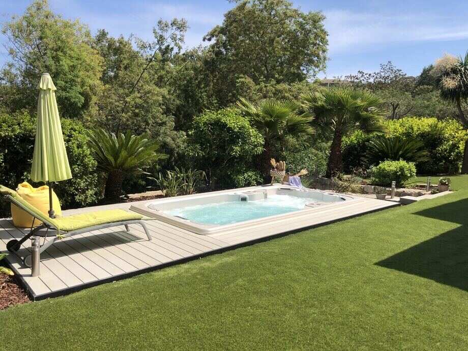 Une mini piscine (spa de nage) est installé dans un jardin.