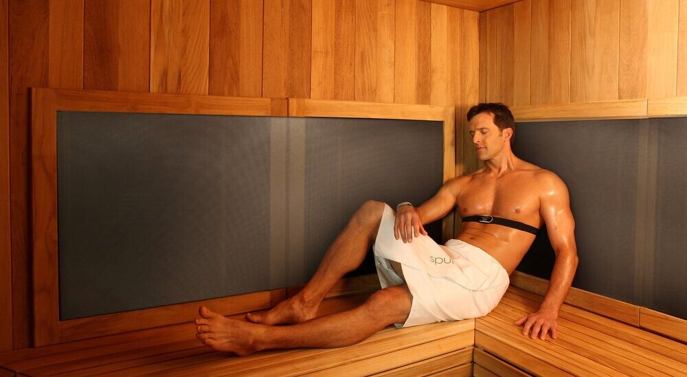 Un homme, bien installé dans un sauna infrarouge, bénéficie des bienfaits prodigués par l'équipement.