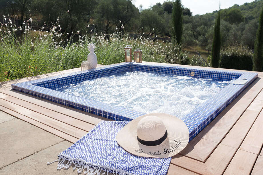 Un spa recouvert de mosaïque est encastré dans une terrasse, et bénéficie d'une vue sur la nature environnante. 