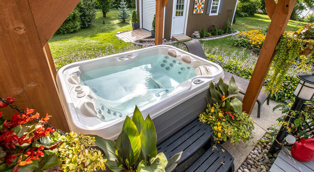 Un bain à remous hors-sol est installé dans un jardin.