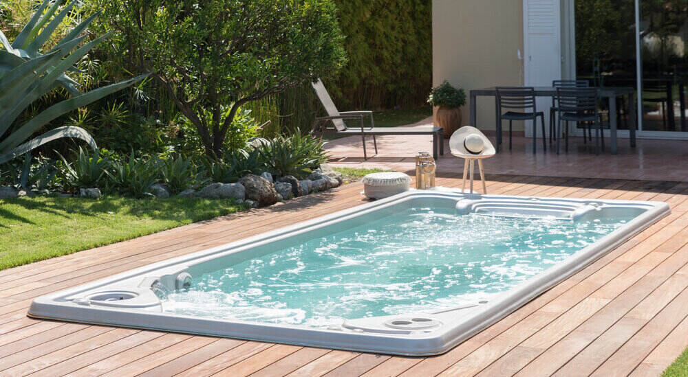 Une mini piscine (spa de nage) est installée dans un jardin.